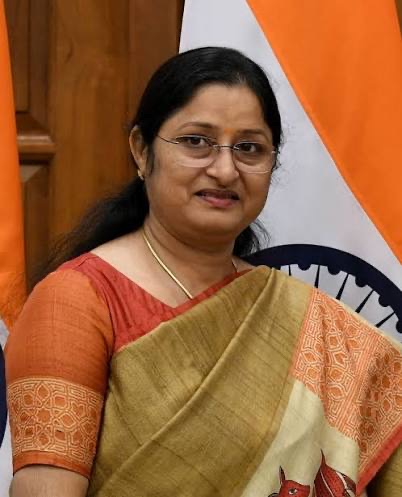 Portrait of Annpurna Devi in a mustard-and-rust silk sari, beside the national flag