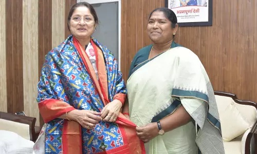 Annpurna Devi, wearing a stole presented to her, stands beside a visitor in a pale green sari in an office