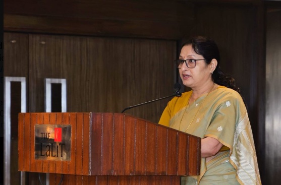 Annpurna Devi speaks at a wooden lectern bearing the name of The LaLiT hotel