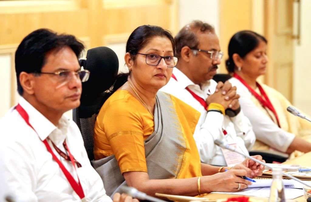 Annpurna Devi, in a saffron-and-grey sari, seated at a conference table with officials wearing lanyards